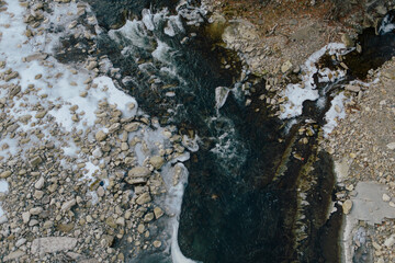 Winter mountain stream among rocks and stones