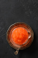 Red caviar on black background. Space for text. Vertical format.