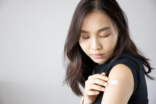 Asian woman receiving getting vaccinated immunity with bandage on her upper arm, concept of innoculation, vaccination, vaccine volunteer or vaccinated patient
