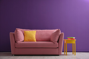 Comfortable pink sofa near purple wall in living room interior