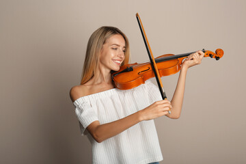 Beautiful woman playing violin on beige background