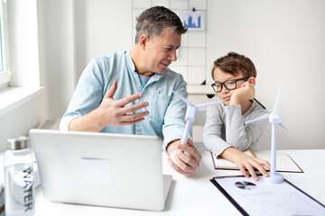 Wind energy concept. Father explains to son his area of ​​responsibility in wind turbine...