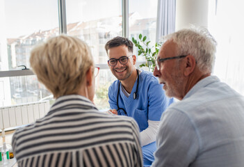 Male nurse talking to seniors patients while being in a home visit.