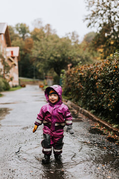 Happy toddler girl standing in puddle