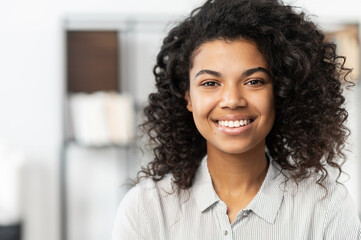 Headshot of a young elegant African American ethnic female with Afro curly hairstyle, beautiful...