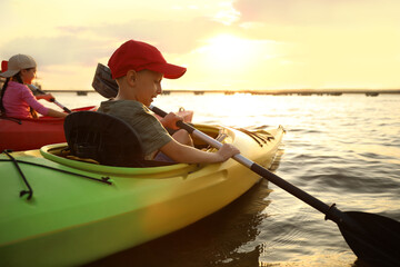 Happy children kayaking on river at sunset. Summer camp activity