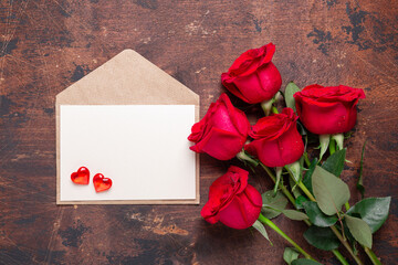 Valentines day greeting card with red roses, envelope and decorative hearts on wooden background. Top view. Copy space - Image