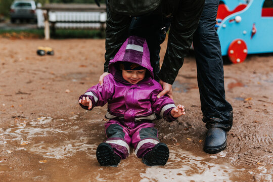 Toddler girl sitting in puddle
