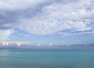 Azure sea water and very light blue sky with white clouds