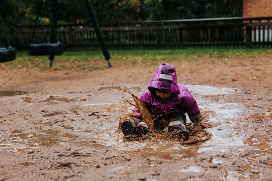 Toddler girl splashing in puddle