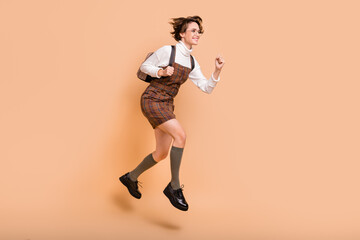 Fototapeta na wymiar Full size profile side photo of young beautiful smiling school girl running in air hold rucksack isolated on beige color background