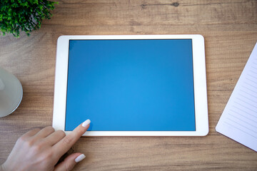 white computer tablet with blue screen and female hand