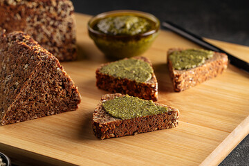 Closeup on sliced triangle flourless diet grain bread spread with pesto sauce