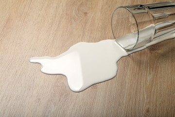 Wooden floor with overturned glass of white milk. Spilled  white milk on a wooden laminate...