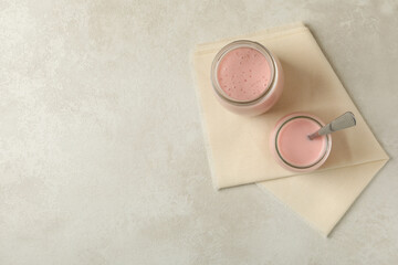 Kitchen napkin with jars of yogurt on white textured background