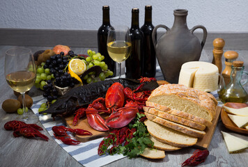 Delicious smoked sturgeon and boiled lobster with crayfishes, fruits and white wine on wooden table.