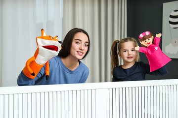 Mother and daughter performing puppet show at home
