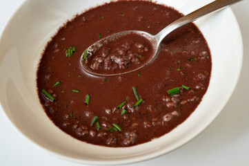 Pork blood soup with groats and chive on white.