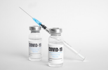 Vials with coronavirus vaccine and syringe on white background