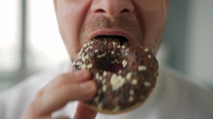 Man eating sweet chocolate donut. Close-up