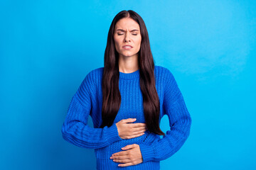 Portrait of brunette sad lady hold stomach wear blue sweater isolated on bright color background