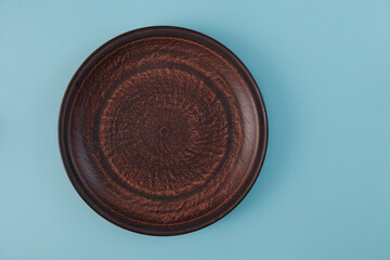 Top view on empty brown clay plate on blue background. rustic dishes