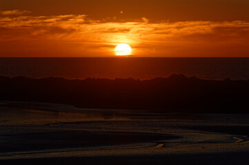 The setting sun, disappearing below the horizon