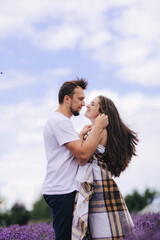 young couple are hugging at the lavender field together on summer day. love story. woman and man in plaid outdoors