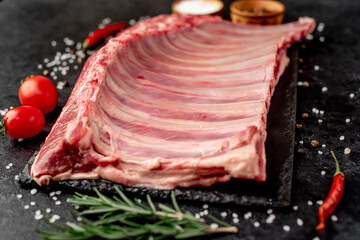 Raw lamb ribs with spices on a stone background