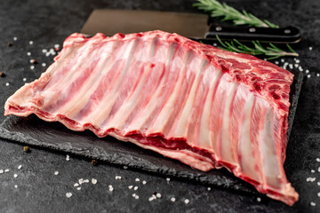 Raw lamb ribs with spices on a stone background
