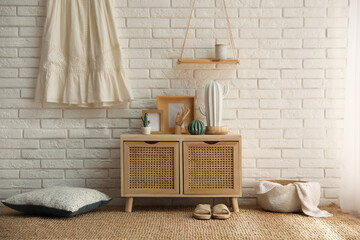 Stylish room interior with wooden cabinet near white brick wall