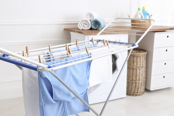 Clean laundry hanging on drying rack indoors - obrazy, fototapety, plakaty