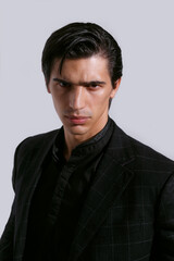 Fototapeta premium Closeup front portrait of a confident handsome young man in black clothing on white background.