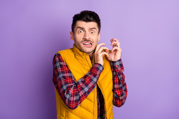 Photo of terrified nervous young man wear yellow sleeveless jacket rising arms isolated violet color background