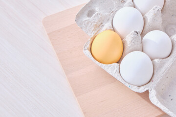 Minimal concept Easter. eggs in a cardboard box and a wooden cutting board on the table