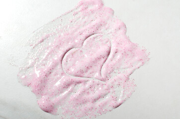 Closeup of shiny pink smear cosmetics and heart symbol on the white background