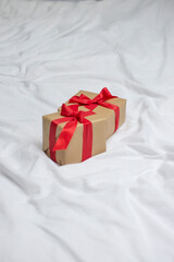 Red gift kraft box with ribbon. Valentine's Day gift in bed. Natural eco and bio gift. Sensual passion minimal gift in bed