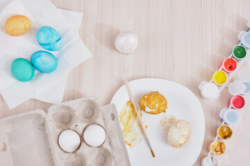 process of painting eggs for easter, eggs box, easter eggs, plate, brushes and paints on the table