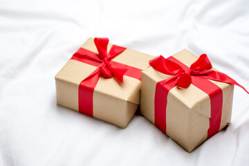 Red gift kraft box with ribbon. Valentine's Day gift in bed. Natural eco and bio gift. Sensual passion minimal gift in bed