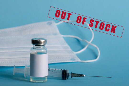 A Medicine Ampoule, A Medical Syringe, And Disposable Masks Are Close-up On A Blue Isolated Background. The Concept Of A Shortage Of Vaccines Against Infection, Influenza, And Coronavirus