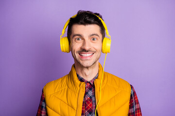 Photo of charming positive young man wear yellow sleeveless jacket headphones smiling isolated...