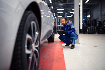 Professional middle aged bearded caucasian car mechanic doing visual inspection of vehicle in...