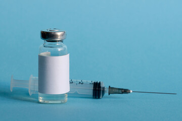 A medicine ampoule and a medical syringe, close-up on a blue isolated background. The concept of...