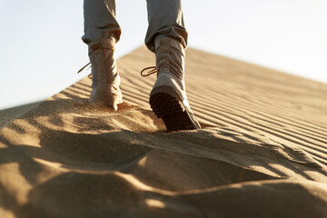 A man walks through the desert in beige pants and boots
