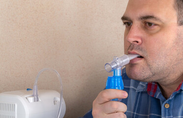 man makes inhalations with the help of nebulizer. patient breathes through an Oxygen Mask. device for nebulization of a medicinal substance. used in the treatment of bronchial asthma and respiratory