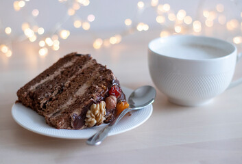 morning coffee in a white mug and a piece of chocolate cake with nuts, on a saucer, on a wooden table, with bokeh in the background. no focus. Hearty breakfast, sugar addiction. Allergenic foods, nuts