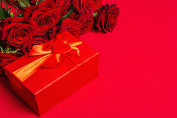 Bouquet of fresh burgundy roses and gift box on a matte red foamiran background