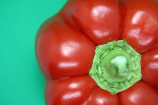 The fruit of a red sweet pepper on a green background.