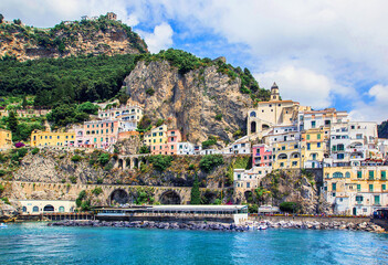 Fototapeta na wymiar Panoramic view, aerial skyline of small haven of Amalfi village with tiny beach and colorful houses located on rock. Tops of mountains on Amalfi coast, Salerno, Campania, Italy