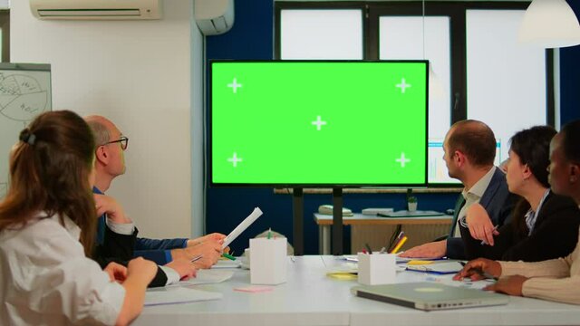 Tv green screen mockup ready for presentation placed in front of desk while business people working in broadroom. Employees using digital chroma key interactive whiteboard with mock up display monitor